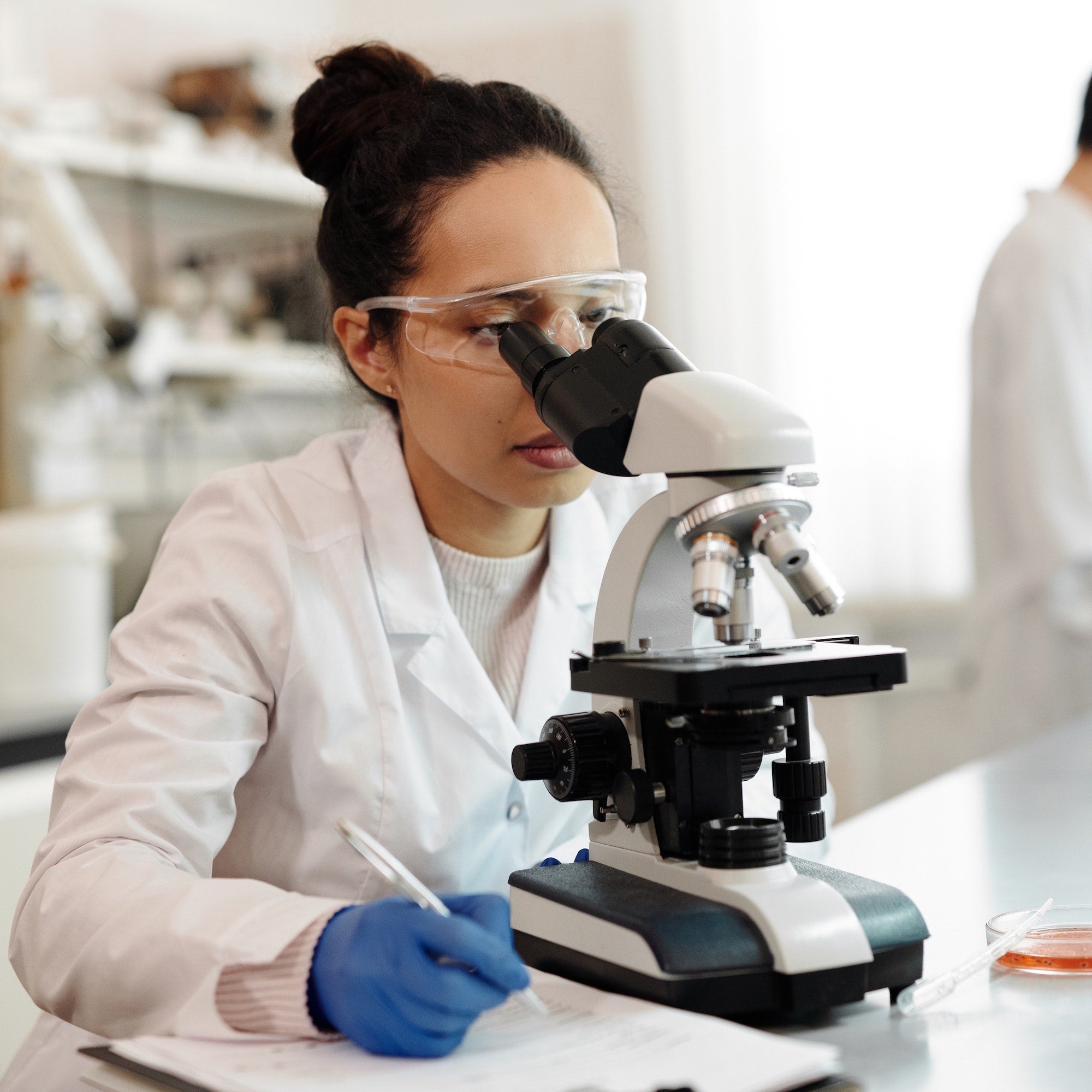 Laboratory Technician Looks into Microscope to Examine A Dietary Supplement Sample